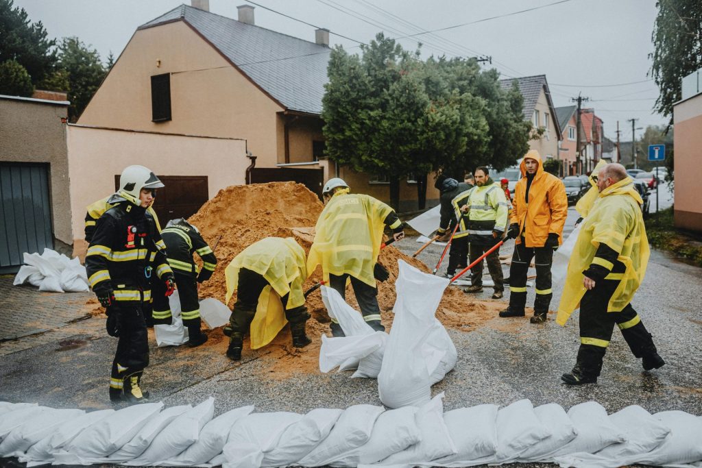 Emergency response team filling sandbags on a rainy street to prevent flooding.