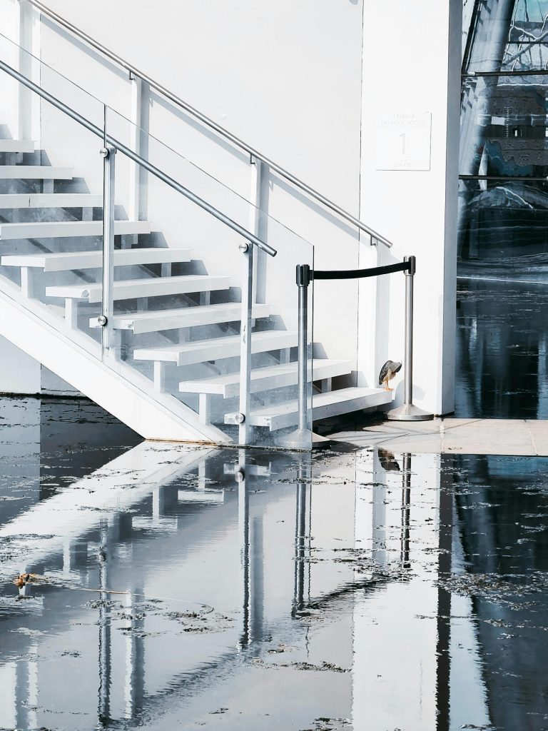 Flooded area with stairs reflecting on water surface, showcasing modern architecture.