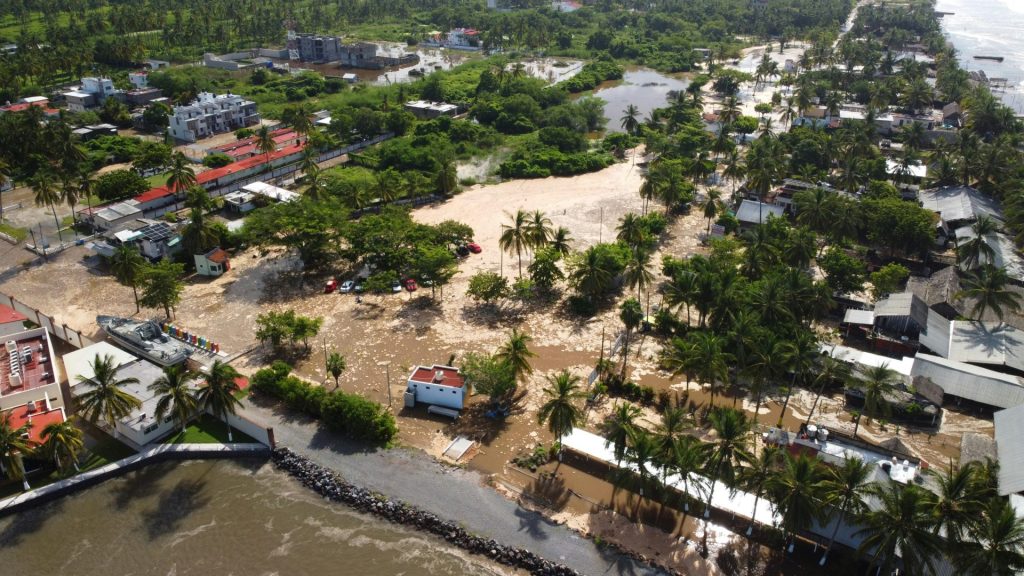Aerial view of flooded coastal town with debris.
