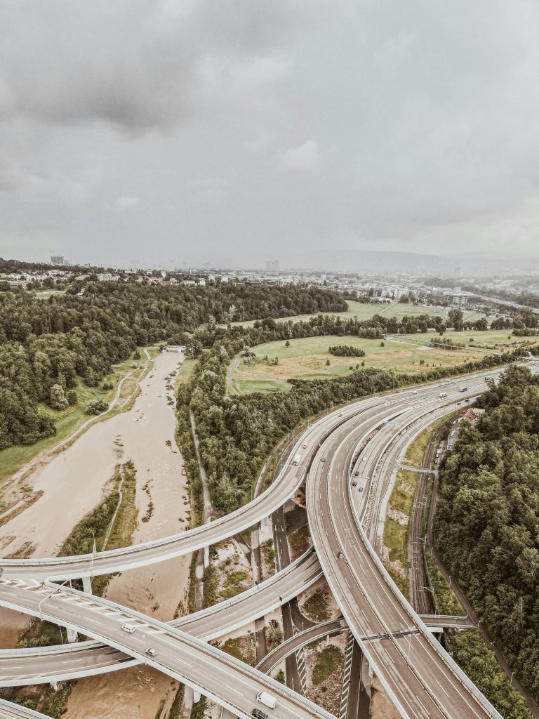 aerial view of road between green trees during daytime