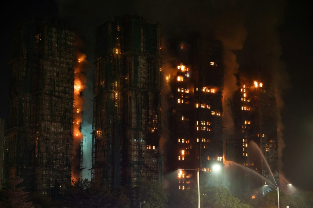 Apartment buildings engulfed in flames at night.